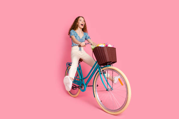istock Happy young woman riding bicycle on pink background 2197553849
