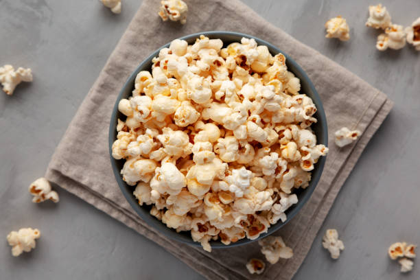Mature couple enjoying while eating popcorn and watching a movie i cinema. Focus is on woman.