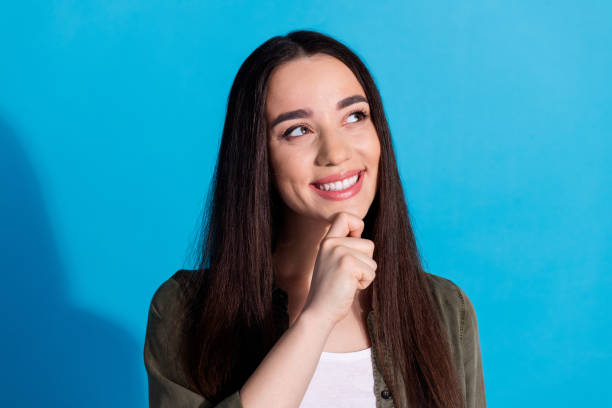 istock Smiling young woman pondering an idea against a vibrant blue backdrop 2197555126