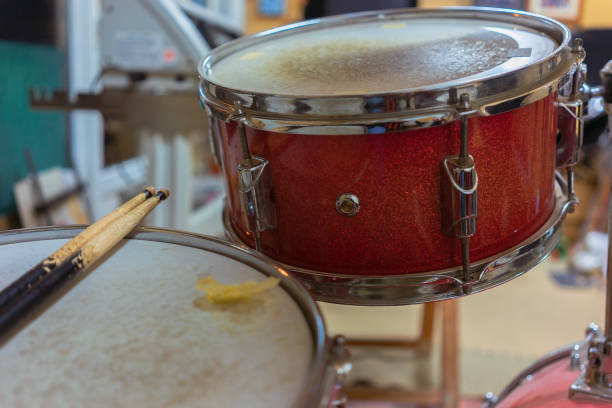 Old drum set close up, red timpani and snare with sticks, hardware details,