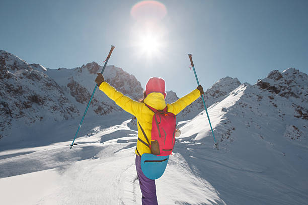 A person clad in a yellow jacket and purple pants is skiing down a snow-covered slope. The individual is confidently navigating the terrain, showcasing skill and agility on skis.