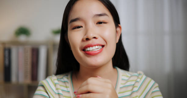 istock Smiling Asian woman using wireless microphone and talking to camera with positive emotion in living room at home. 2197556036