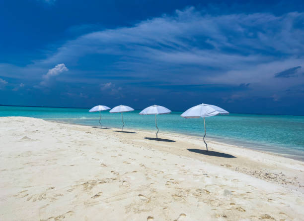 Summer tropical with white umbrella on the beach with  blue sky background