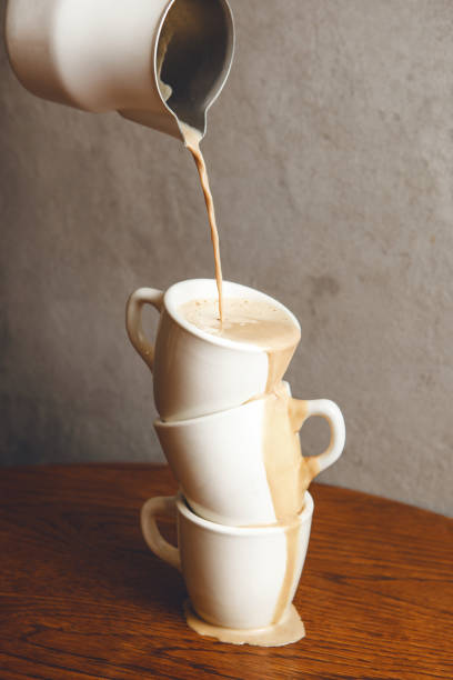 istock Milk-based Coffee Being Poured Into Stacked Cups With Liquid Flowing Over the Edges. 2197560105