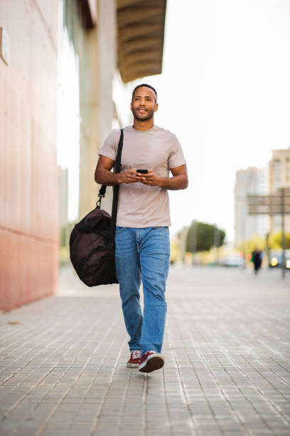 istock Young man with smart phone and bag outdoors in city 2197562147