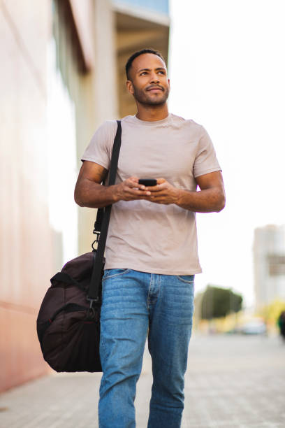 istock Young guy with mobile phone and bag outdoors in city 2197562150
