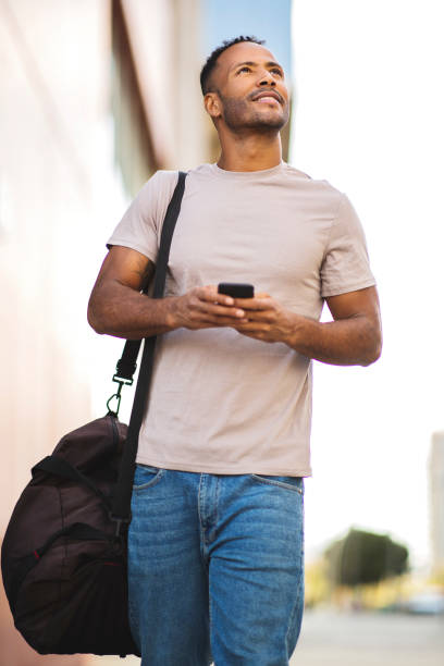 istock Man with smart phone and bag looking up outdoors in city 2197562157