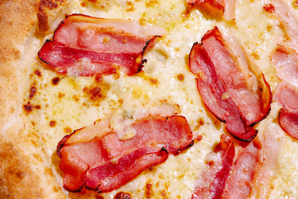 A delicious pizza features crispy bacon slices atop a gooey layer of melted cheese. The golden crust is perfectly baked, enticing anyone nearby to take a slice.