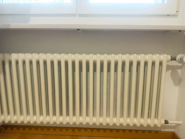 istock White Cast Iron Radiator Under a Window in a Home Interior 2197563818