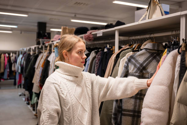 istock Woman browsing clothes in a thrift shop. Second hand concept 2197564250