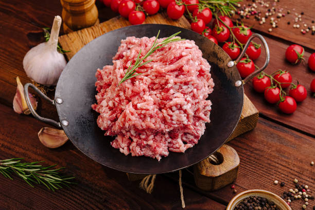 istock Freshly minced meat on a wooden table surrounded by spices and tomatoes ready for cooking 2197564478