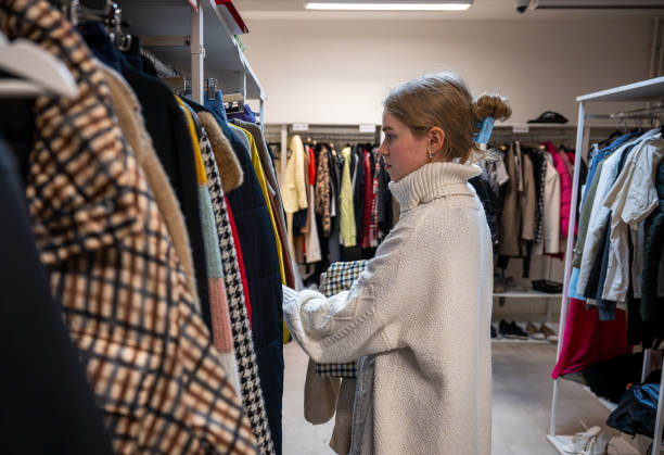 istock Woman browsing clothes in a thrift shop. Second hand concept 2197564640
