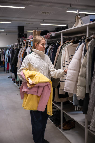 istock Woman browsing clothing racks in a thrift shop. 2197564648
