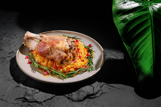 Savory meat dish garnished with pomegranate and herbs on a rustic plate with green foliage