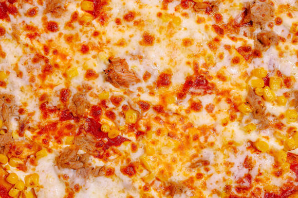 A closeup view of a pizza topped with pepperoni, corn, onions, and jalapeos