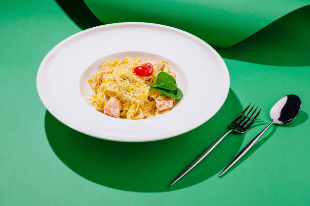 istock Pasta dish with salmon, cheese, and cherry tomatoes served on a vibrant green background 2197567237