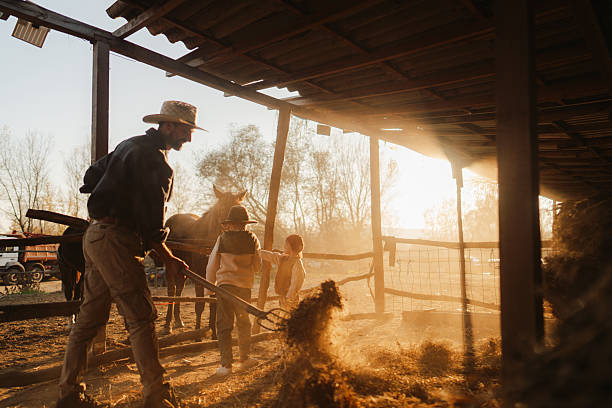 Photo of a little boy helping his dad and sharing some precious moments with him at their horse ranch