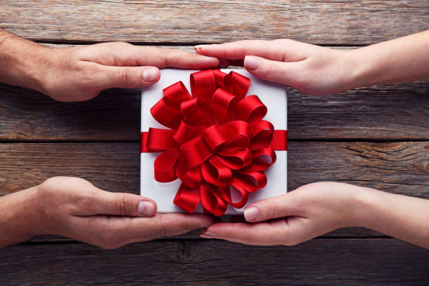 istock Female hands holding gift box with ribbon on wooden table 2197568690