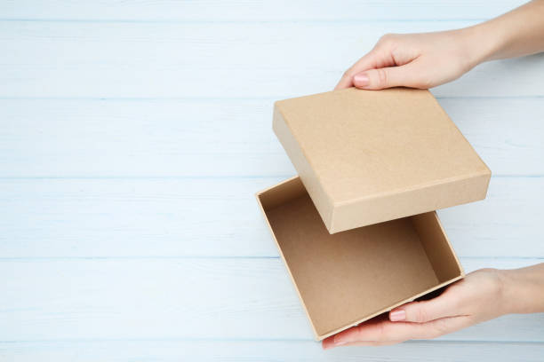 istock Female hands opening gift box on wooden table 2197569644