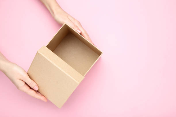istock Female hands opening brown gift box on pink background 2197570368