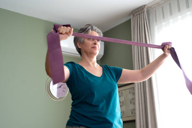 istock Middle aged woman doing stretching exercises with blue stretch band or gymnastic band 2197574467
