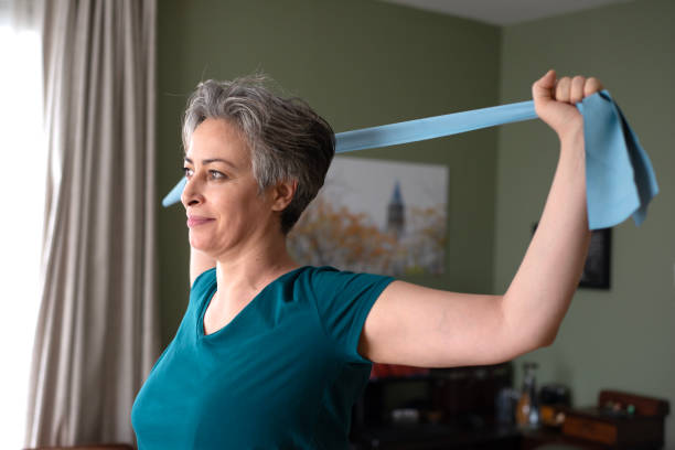 istock Middle aged woman doing stretching exercises with blue stretch band or gymnastic band 2197574506