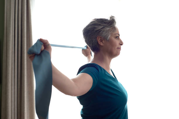 istock Middle aged woman doing stretching exercises with blue stretch band or gymnastic band 2197574632