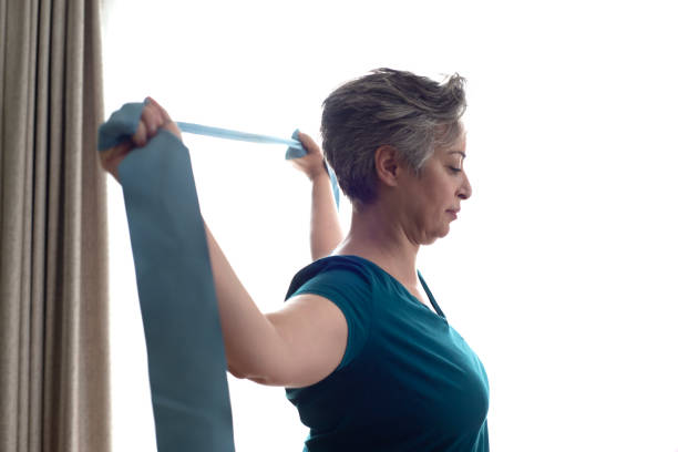 istock Middle aged woman doing stretching exercises with blue stretch band or gymnastic band 2197574669