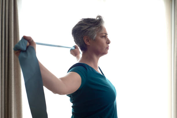 istock Middle aged woman doing stretching exercises with blue stretch band or gymnastic band 2197574763