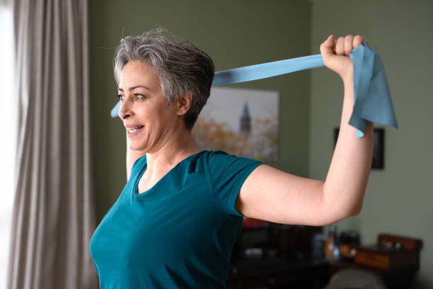 istock Middle aged woman doing stretching exercises with blue stretch band or gymnastic band 2197574877