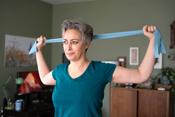 istock Middle aged woman doing stretching exercises with blue stretch band or gymnastic band 2197574894