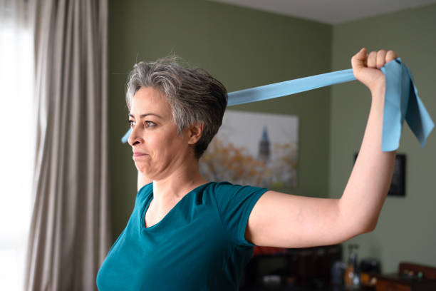 istock Middle aged woman doing stretching exercises with blue stretch band or gymnastic band 2197574905