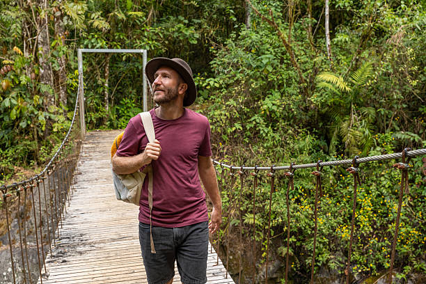 istock Man Walking on Jungle Suspension Bridge with Backpack 2197575110