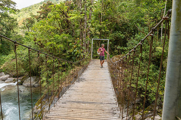 istock Man Walking on Jungle Suspension Bridge with Backpack 2197575142