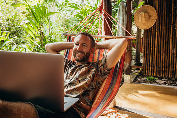 istock Man Relaxing in Hammock with Laptop in Tropical Setting 2197575207