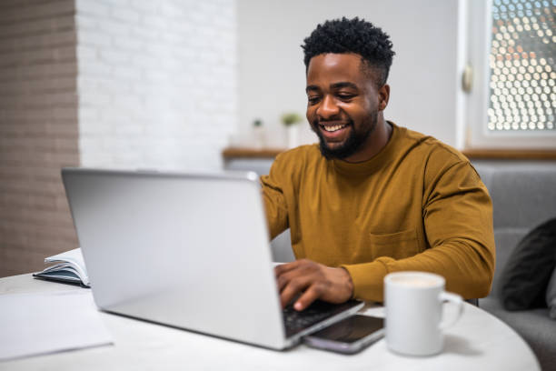 istock Smiling African-American man working on a laptop at his home 2197575393