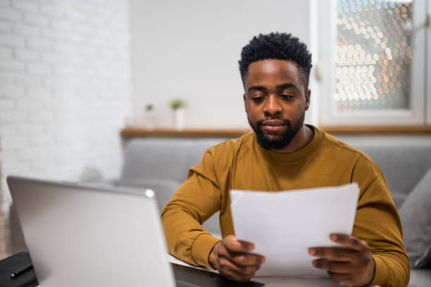 istock African businessman examining documents and using laptop at home 2197575561