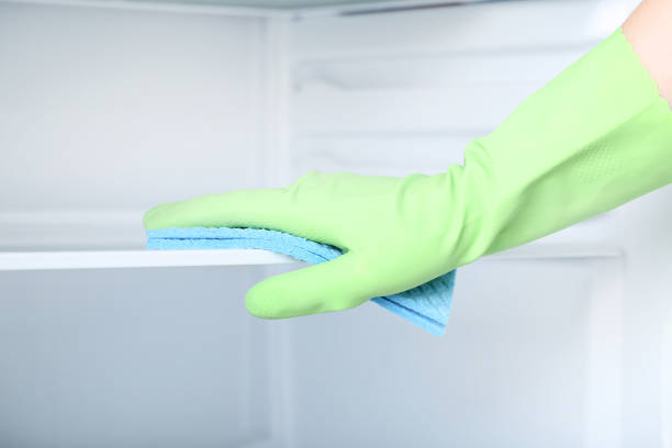 istock Hand in glove with sponge cleaning refrigerator 2197576275