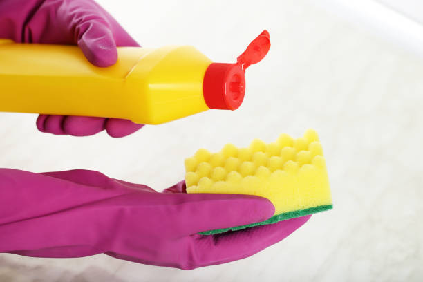 istock Hands in gloves with sponge and bottle of detergent cleaning kitchen table 2197577842