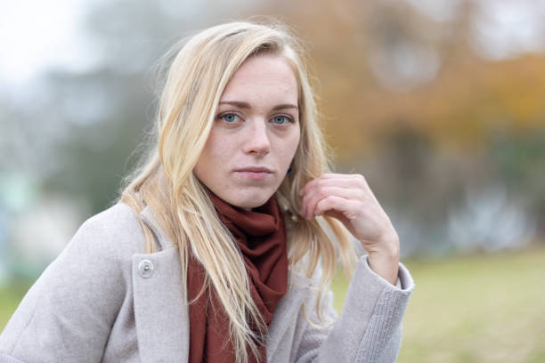 istock Blonde woman touching hair while posing in park 2197582219