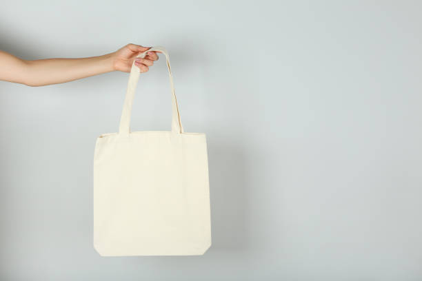 istock Female hand holding white cotton eco bag on grey background 2197582877