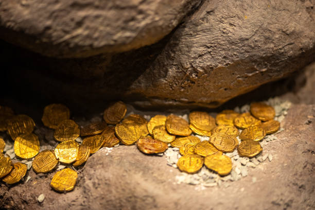 Authentic colonial-era gold coins from Latin America scattered on rugged stone surfaces, resembling a recently unearthed treasure. The scene evokes a sense of historical richness and adventurous discovery.
