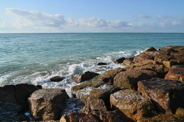 istock Calm waves crash gently against rugged rocks at a serene coastal spot under a clear blue sky 2197585254