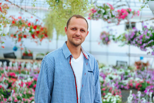 istock A young handsome farmer stands in a greenhouse and looking at camera. 2197589505