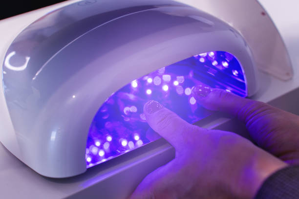 istock Client's hands under UV nail lamp during the gel manicure curing process 2197589653