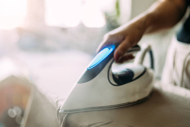 istock Ironing Clothes with Moden Steam Iron in Bright Daylight at Home 2197593242