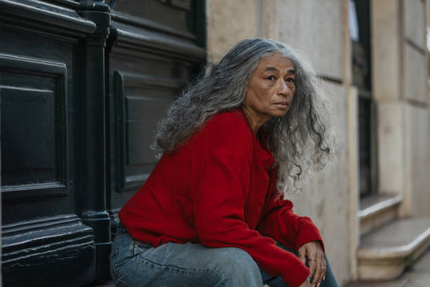 Aged homeless woman. Aged homeless woman feeling hungry and lonely sitting alone outside