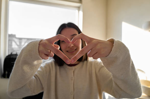 istock Young adult woman making heart shape gesture 2197597662