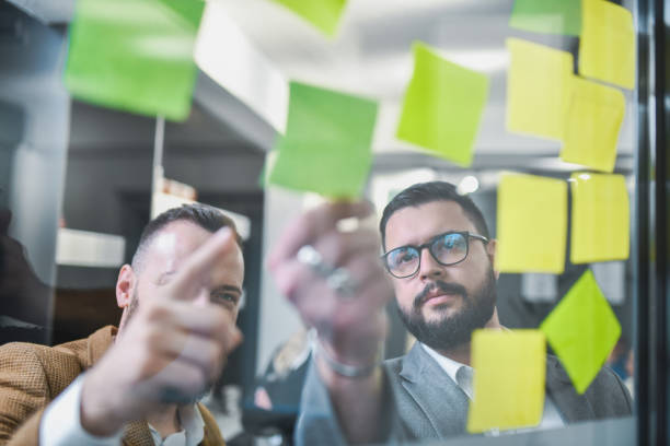 istock Male Entrepreneurs Discussing How to Improve Their Business Reading Notes From Sticky Papers 2197601741