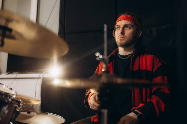 istock Handsome Young Drummer Performing on Concert Stage with His Band Members, Surrounded by Falling Confetti and Pulsating Visuals. Young Musicians Showcasing Their Skills and Energy. Slow Motion Footage 2197602079